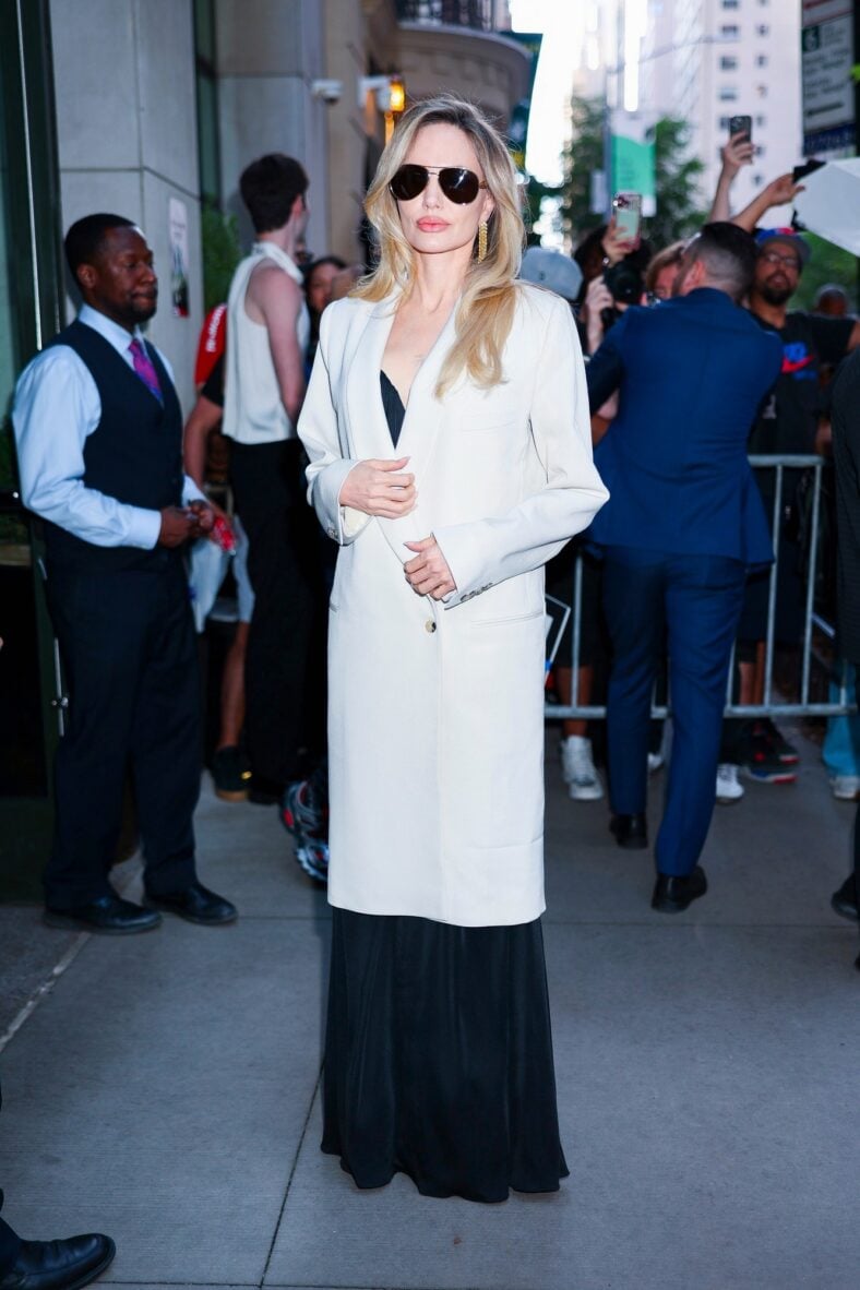 Angelina Jolie attends screening for "Couture" in simple black gown with cream overcoat on top and sunglasses