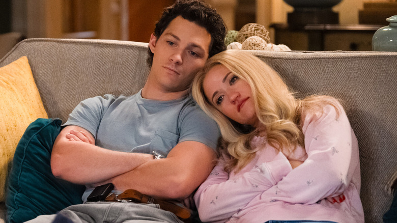 Georgie in a gray shirt and Mandy in a pink shirt sitting on a couch and leaning on one another with sad expressions in Georgie and Mandy's First Marriage