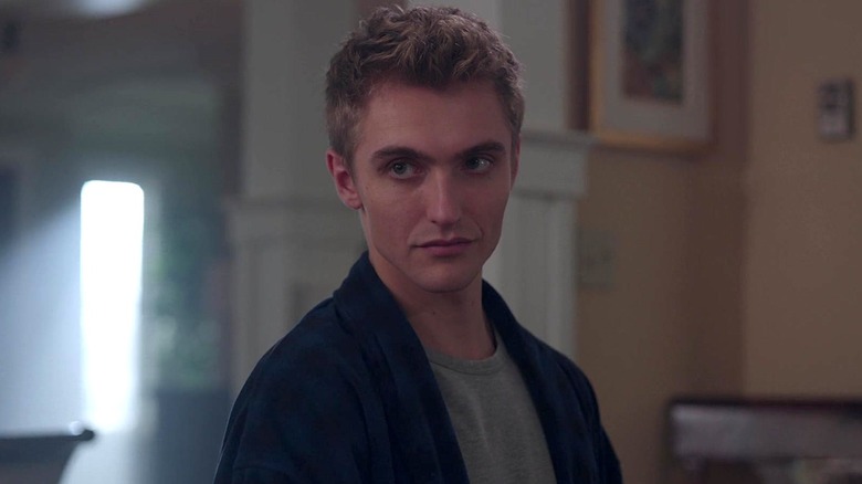 Chic in a gray shirt and blue jacket standing in a house in Riverdale