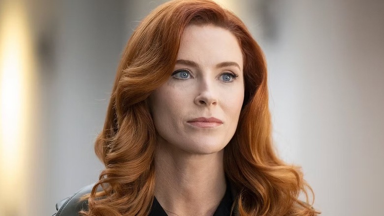 Monica (Bridget Regan) standing in a grey-painted room on 