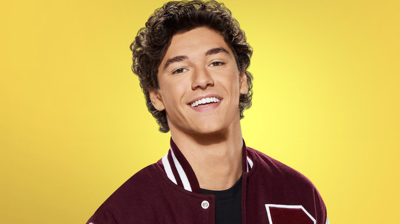 Jamie Spano wearing a red varsity jacket and smiling in front of a yellow background on a character poster for Saved by the Bell reboot
