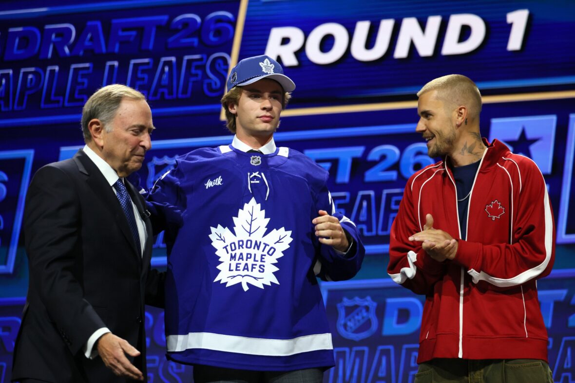 NHL commissioner Gary Bettman hands Gavin McKenna of Canada hat as singer Justin Bieber looks on after McKenna