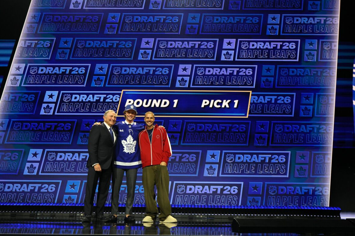 NHL commissioner Gary Bettman hands Gavin McKenna of Canada hat as singer Justin Bieber looks on after McKenna