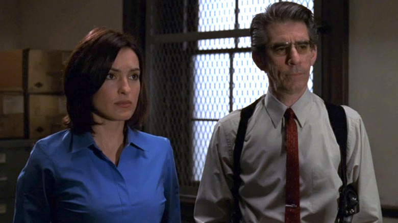 Olivia Benson in a blue shirt standing next to John Munch in a grey shirt in Law & Order: SVU