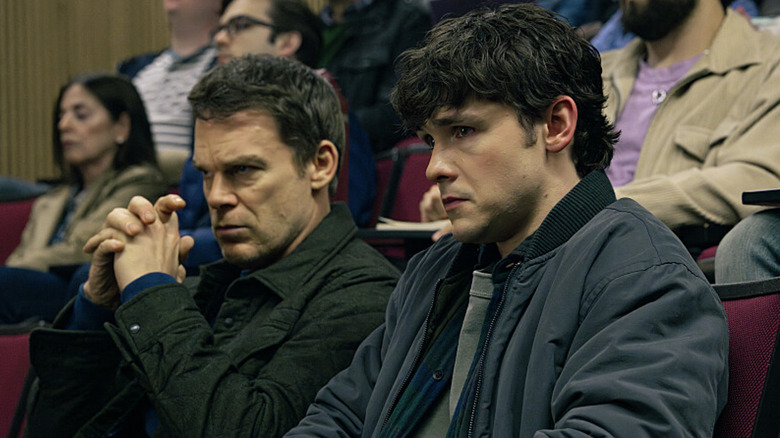 Dexter and Harrison seated next to each other wearing jackets in Dexter: Resurrection