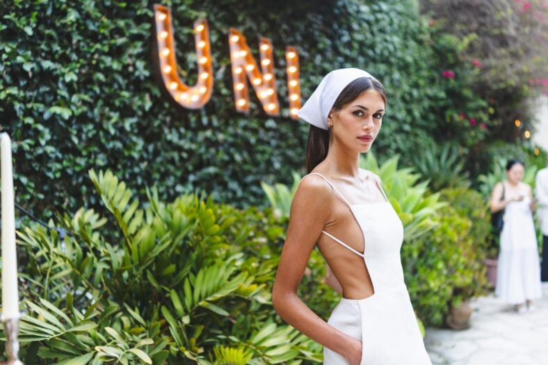 Kaia Gerber wears a white Calvin Klein Collection mini dress and matching headscarf.