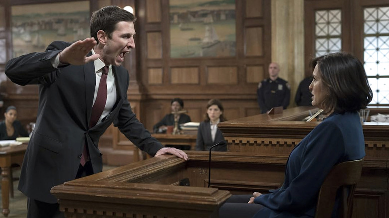 William Lewis in a suit yelling as a seated Olivia Benson with his hand raised in a courtroom in Law and Order: SVU