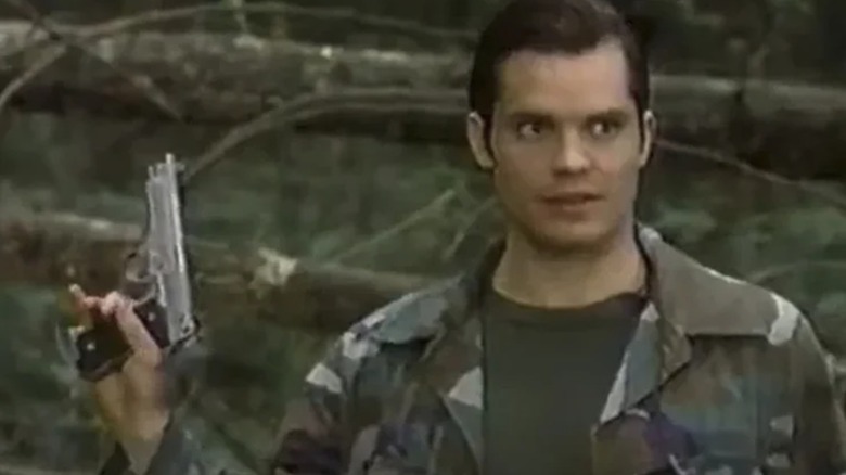 Scooby (Timothy Olyphant) holding a gun in the woods in 
