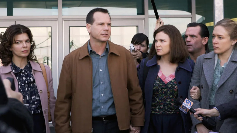 Jeanne Tripplehorn (Barbara Henrickson), Bill Paxton (Bill Henrickson), Chloë Sevigny (Nicolette Grant), and Ginnifer Goodwin (Margene Heffman) walk hand in hand outside a building with concerned expressions as reporters surround them with microphones, cameras, and tape recorders