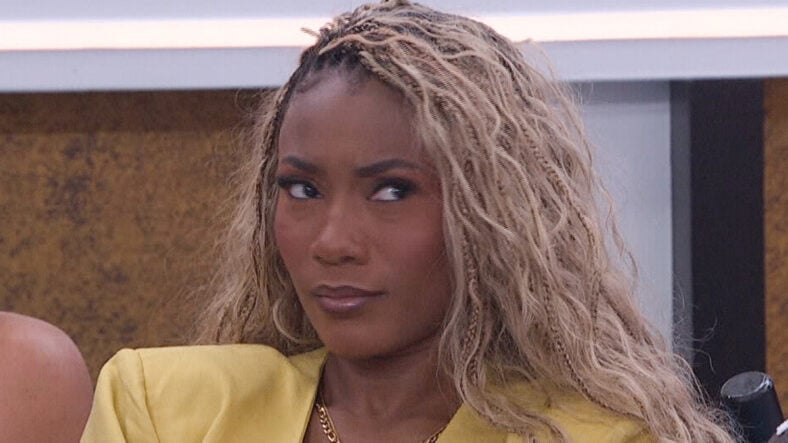 Taylor from Big Brother 28 looking skeptical. Her hair is down and she's wearing yellow and looking to one side