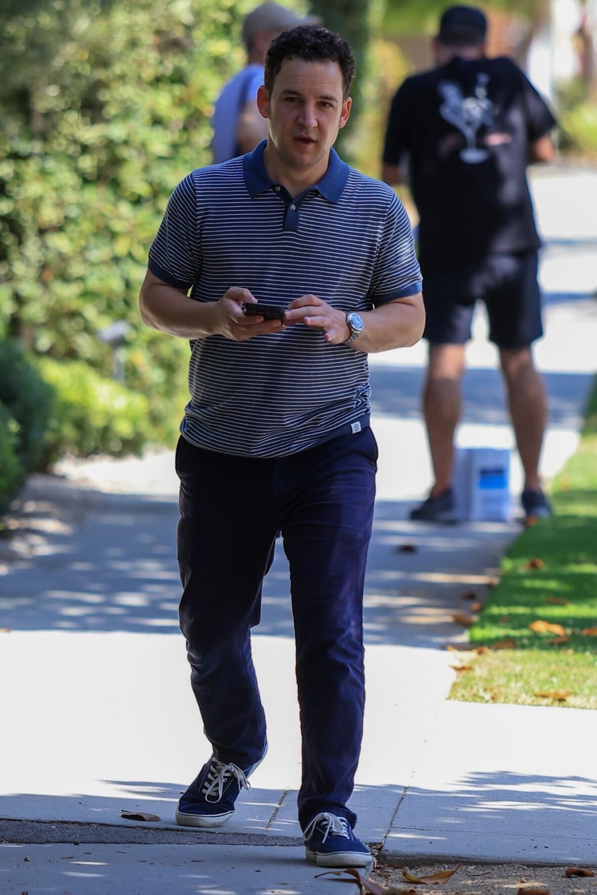 Ben Savage walking on a sidewalk in Santa Monica holding his cell phone and speaking