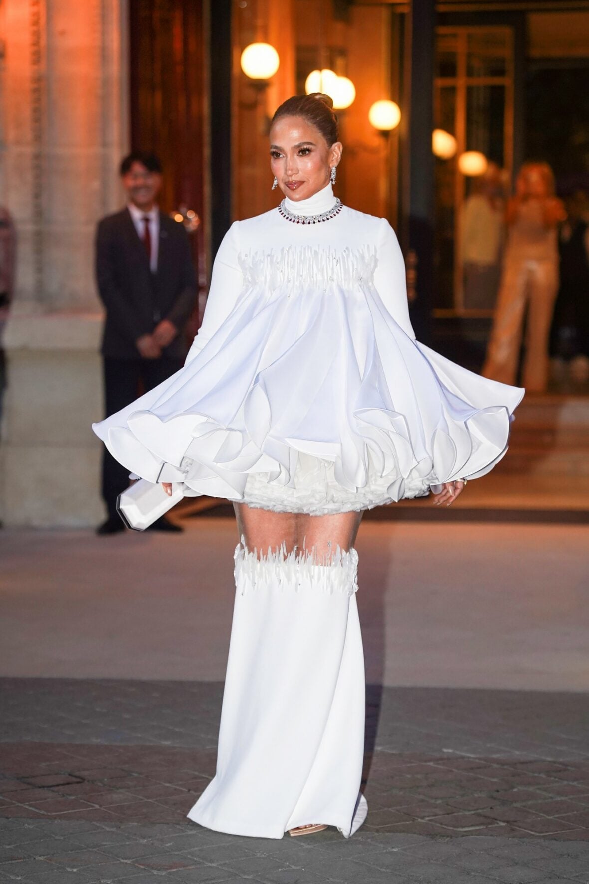 Jennifer Lopez in a white embellished high-neck dress with matching boots