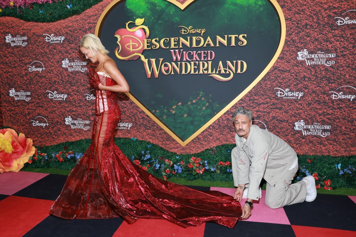 Taika Waititi helps Rita Ora with her dress at Descendants: Wicked Wonderland premiere