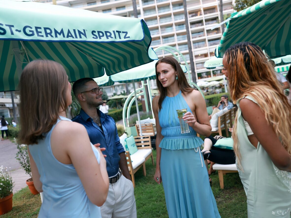 Sophie Turner wears chiffon wrap top and skirt while posing with guests at St. Germain's pop-up in Cannes