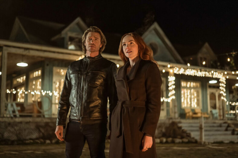 Morgan Kahan and Chad Michael Murray standing together in front of a lit up house in a nighttime scene for Sullivan's Crossing
