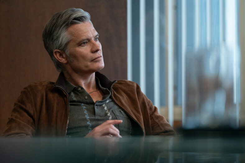 Timothy Olyphant shown sitting at a table in a still from Lucky episode 6.
