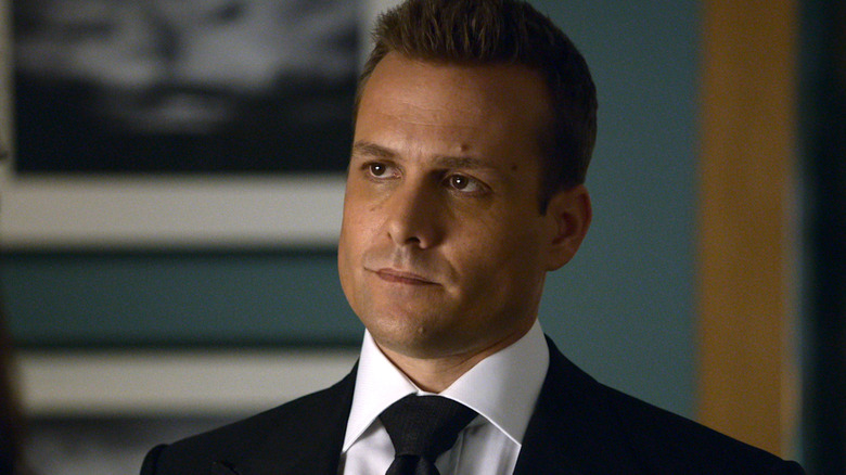 Gabriel Macht with short brown hair and wearing a black suit.